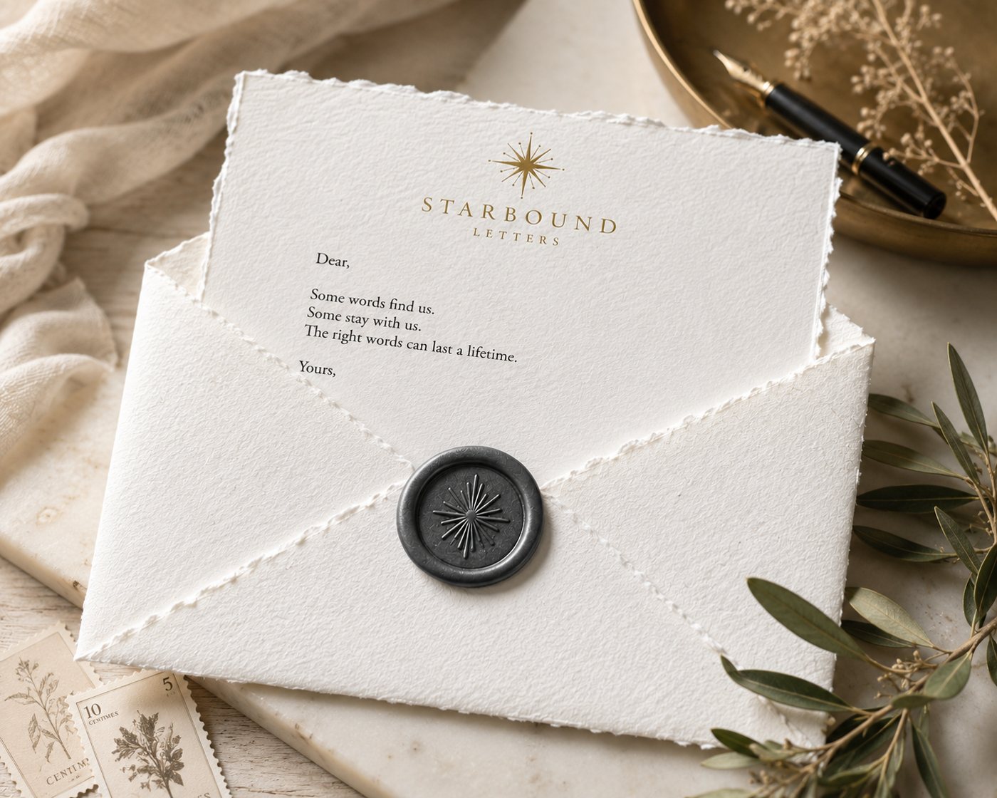 A Starbound letter on handmade paper emerging from its white envelope, sealed with charcoal wax